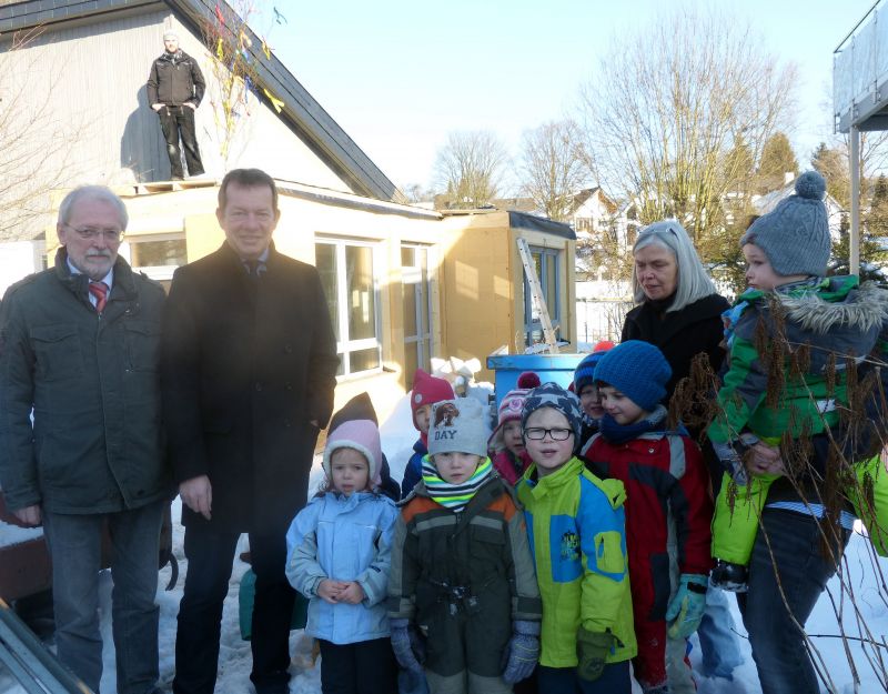 Zum traditionellen Richtspruch des Zimmermanns trafen sich die Gäste des Richtfests vor dem neuen Anbau: (v.l.) AWO-Vorstandsvorsitzender Karl-Ludwig Völkel, Bürgermeister Steffen Mues und Kita-Leiterin Dagmar Friese mit Kindergarten-Kindern. (Foto: Stadt Siegen)