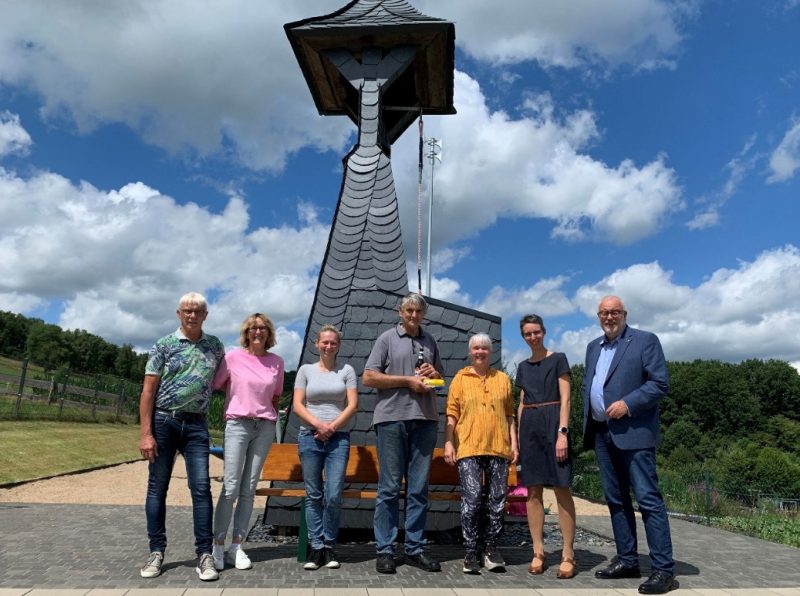 Mitglieder des Dorfvereins Obere Hees vor ihrem grundsanierten Wahrzeichen, dem Glockenturm, am neuen Dorfplatz mit Stadtbaurätin Christina Eckstein und Bürgermeister Walter Kiß (beide ganz rechts).